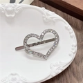 Macro shot of a heart-shaped rhinestone hair clip on a vintage white decorative tray - Heart / White