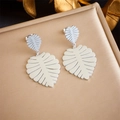 Macro detail of silver monstera leaf earrings on golden textured metallic surface - Monstera Leaf Stud Style (E5761 Steel Color)