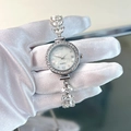 Detalle macro de reloj plateado con brazalete de pedrería en forma de hoja y esfera de nácar - Plateado