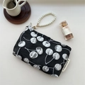 Close-up of cherry jacquard pattern and pearl handle on a sleek black storage pouch - Black Cherry