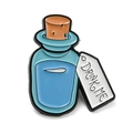 Cute enamel brooch featuring a blue Alice Drink Me bottle with a small white hanging tag - Alice DRINK ME Bottle