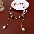Detail einer Vintage-Kette mit Perlen, Tigerauge-Steinen und goldenen Doppelkettenschichten - Gold-Weiß-Kaffee (Tigerauge)