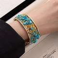 Detail of gold wide open cuff bracelet with sky blue stones and sparkling crystals - Blue