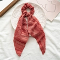 Detail of red pleated fabric scrunchie with long ribbons on a white embossed plate - Style with Streamer / Orange