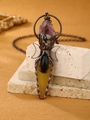 Macro detail of vintage bronze pendant featuring purple crystal and moon motifs - Yellow