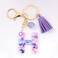 Close-up of letter H resin keychain with colorful stones and purple tassel detail - Letter H
