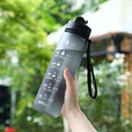 Gray gradient frosted sports water bottle with straw and time markers held in hand - 1000ml / Black