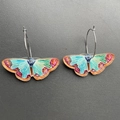 Macro detail of colorful butterfly earrings with turquoise wings and silver metal hoops - K51 Blue Moth