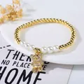 Detailed shot of a gold bear pendant with rhinestones and white pearls on a beaded bracelet - 3D Full Stone Bear