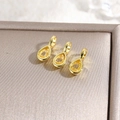 Detailed macro view of three 18k gold plated teardrop pendants with yellow zircon stones - Yellow