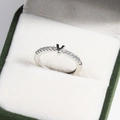 Close-up of V-shaped silver ring with inset gemstones in a green velvet jewelry box - Platinum V