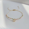 Böhmisches Armband mit bunten Miyuki-Perlen und goldenem Buchstaben-C-Anhänger auf weißem Grund - Buchstabe C