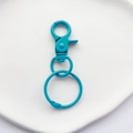 Detail view of sky blue lacquered metal lobster clasp and ring on a white tray - Blue