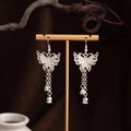 Silver Miao style butterfly tassel earrings with bells hanging on a gold display stand - Butterfly Bell Tassel (E2874-27) / Silver