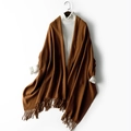 Chic brown thick knitted wool scarf with fringe trim styled over a white turtleneck - Caramel color