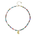 Detailed shot of beaded necklace with gold letter E pendant and heart charm on extension chain - Letter E
