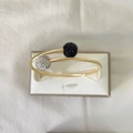 Détail d'un bracelet torsadé en or 18k avec embouts sphériques sertis de cristaux - Or/Noir et Blanc