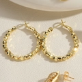 Macro shot of gold beaded hoop earrings with faceted metallic beads and secure clasp - Gold Metal Beaded Round Hoop Earrings