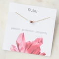 Delicate gold cross chain necklace with ruby stone bead on display card - Ruby