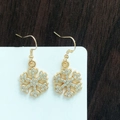 Detailed close-up of gold snowflake earrings with sparkling white rhinestones on display - Luxurious Gold Snowflake with Crystals