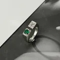 Minimalistischer silberner Ring mit grünem Edelstein und Sternmuster auf Hintergrund - Offener Sternförmiger Grüner Edelsteinstil