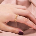 Detail shot of a wavy 18K gold ring with zircons worn on index finger over silk fabric - Gold Wave Pattern