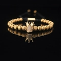 Golden crown bracelet with sparkling zircons and woven cord on black reflective surface - Gold Crown with White Zircon