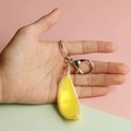 Handheld realistic yellow lemon slice keychain with silver metal ring and clasp detail - Lemon Wedge