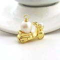 Macro detail of golden motorcycle pendant with large white pearl on white ceramic - Gold Pearl Motorcycle (05)