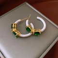 Detail of green gemstone and white enamel C-shape floral earrings on jewelry box - Emerald Gemstone White Enamel Style