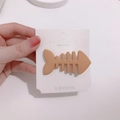 Cute matte orange fishbone hair clip attached to white brand packaging card - Khaki