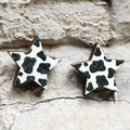 Detailed view of star-shaped earrings with cow print pattern on a rustic stone background - 13-Cow Print Star