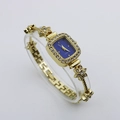 Detail of a luxury gold bangle watch with floral diamond inlay and a navy blue dial - Gold Case Blue Dial