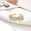 Macro view of gold 18K plated evil eye ring with white zircon on white fabric - Light Blue and White Eye (ZYN-DMR56G-5)