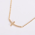 Gros plan d'un collier croix horizontale plaqué or avec cristaux de zircone brillants - Doré