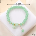 Bracelet en perles de cristal vert clair avec breloques de muguet et détails dorés - Style Muguet Verre Vert