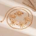 Close-up of golden chain belt with sun face pendants on textured beige background - Gold