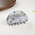 Close-up of large half-moon hair claw clip with spider web pattern and gold spring - White Spider Web / 8.2cm