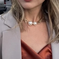 Detail of chunky gold chain necklace with large twin pearls on a model neck - Gold
