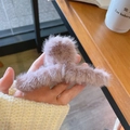 Chic mauve plush faux fur hair claw clip for women held against a warm wooden background - Purple Plush Hair Claw