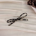 Leopard print bow hair clip with a slim design placed on elegant beige silk fabric - Deep Leopard Bow
