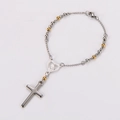 Dettaglio macro di medaglia a cuore in acciaio e ciondolo a croce su bracciale religioso - Oro e Argento / 17+3cm