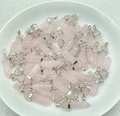 Detail von Rosenquarz-Sechskantanhängern mit silbernen Ösen auf beigem Leinenhintergrund - Anhänger mit Halskette / Rosa Jade