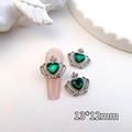 Macro shot of a vintage crown nail charm with a green heart gem and silver frame - Silver-Green