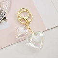 Close-up of double acrylic heart keychain with holographic finish and golden clasp - White