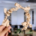 Close-up of knotted champagne gold satin headband detail with smooth texture finish - Light Gold (Satin Knot)