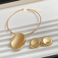 Detailed view of gold oval pendant necklace and round button stud earrings on tray - Gold Oval Jewelry Set
