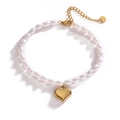 Elegant white pearl bracelet with a polished 18K gold heart pendant on a white background - Gold