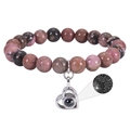 Macro shot of silver heart pendant with projection stone on pink zebra stone bracelet - Rhodonite