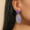 Purple oval Christmas earrings with festive motifs worn by a model in soft lighting - Purple Christmas Snowman Print Style